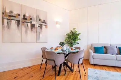 a dining room with a table and chairs and a couch at Bright Flat few steps to Aliados Av by LovelyStay in Porto