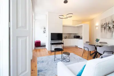 a living room with a white couch and a table at Bright Flat few steps to Aliados Av by LovelyStay in Porto