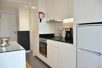 a kitchen with white cabinets and a stove top oven at Central with balcony - 9 min-walk to Trindade in Porto