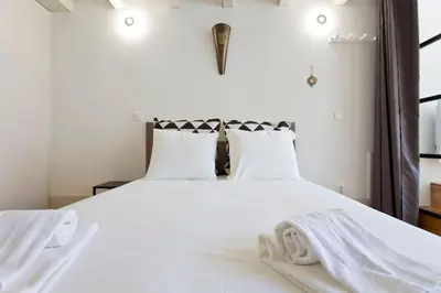 a bedroom with a white bed with white sheets and pillows at Aposentus - Premium Central Apartment 3BR in Porto