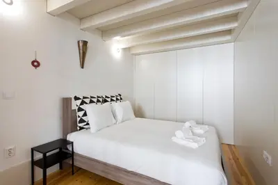 a small bedroom with a white bed and a black table at Aposentus - Premium Central Apartment 3BR in Porto