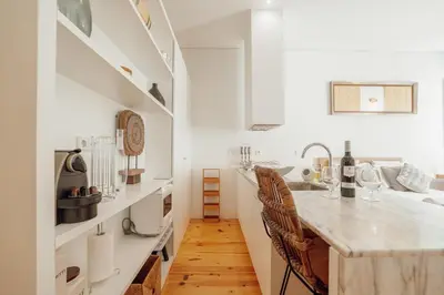 a kitchen with white walls and a counter with chairs at Flores Premium by Hosty in Porto