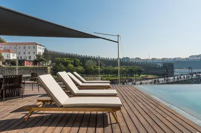 a row of lounge chairs sitting on a deck next to the water at GuestReady - D. Hugo Boutique Hotel B&B in Porto