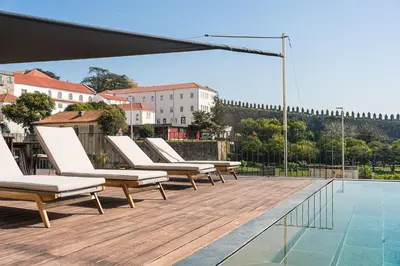 a row of lounge chairs sitting on a deck next to a swimming pool at GuestReady - D. Hugo Boutique Hotel B&B in Porto