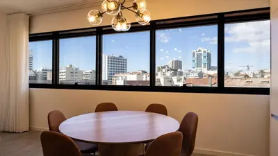 a table and chairs in a room with a large window at Bright 2BR Flat near Praça da Galiza by LovelyStay in Porto