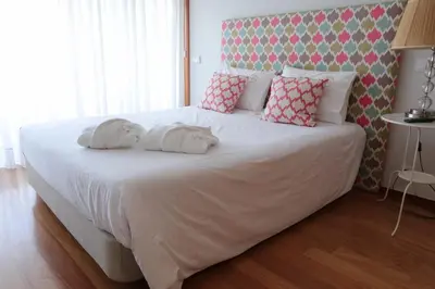 a large white bed with pillows on top of it at Refúgio Douro à Vista in Porto