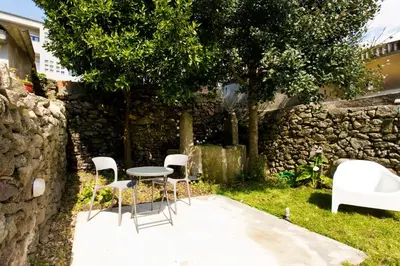 a table and chairs in front of a stone wall at Gabi's House in Porto