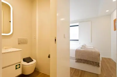 a bathroom with a bed and a toilet and a window at Gabi's House in Porto
