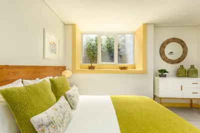 a bedroom with a bed with green pillows and a window at São Miguel Apartments in Porto