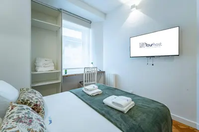 a bedroom with a bed with a desk and a window at New Alegria in Town 1 in Porto