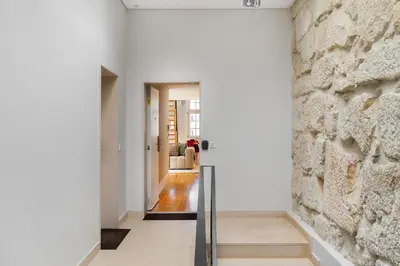a hallway with white walls and a stone wall at WHome Trendy Cedofeita Loft - Luxe & Light-Filled in Porto