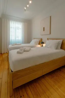 two beds in a bedroom with wooden floors at The Cale - Porto, Firmeza 1 in Porto
