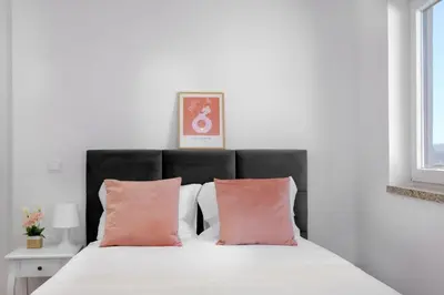 a bedroom with a bed with two pink pillows at Riverside Studio By Luís Bridge, WOW & Half Rabbit in Vila Nova de Gaia