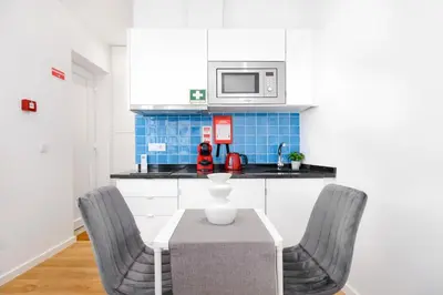 a kitchen with a table with chairs and a microwave at Cozy Studio 2 min walk to Douro River with AC in Vila Nova de Gaia