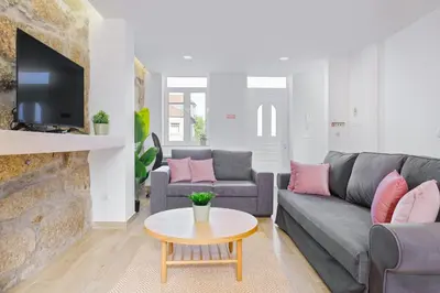 a living room with a gray couch and pink pillows at Sunny House with Patio, Walk to Attractions in Vila Nova de Gaia