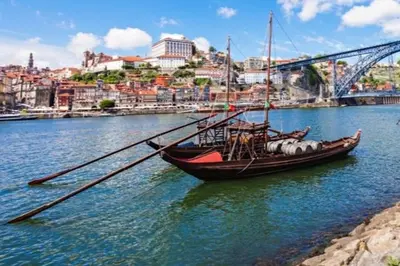 a boat sitting in the water next to a bridge at 2-Studio House Steps from Best Attractions of Porto in Vila Nova de Gaia