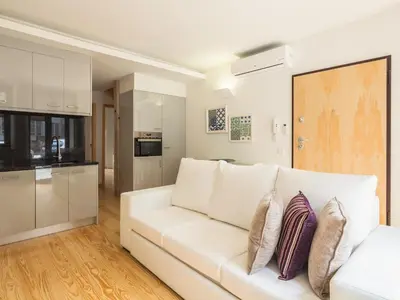 a living room with a white couch and a kitchen at Trindade by Guestify in Porto
