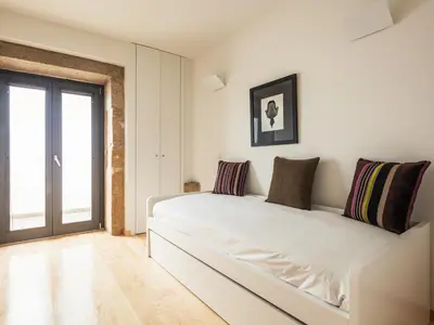 a white bedroom with a large white bed with pillows at Trindade by Guestify in Porto