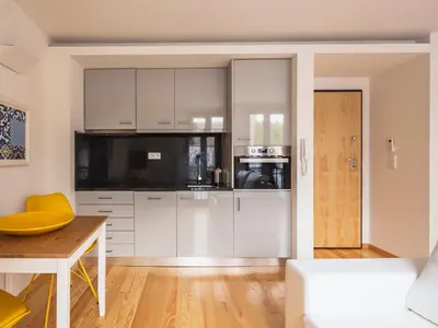 a kitchen with white cabinets and a wooden table at Trindade by Guestify in Porto