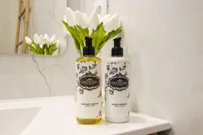 two bottles of soap sitting on a bathroom counter with white flowers at Luxury Style 4 with AC Downtown Porto near Metro in Porto