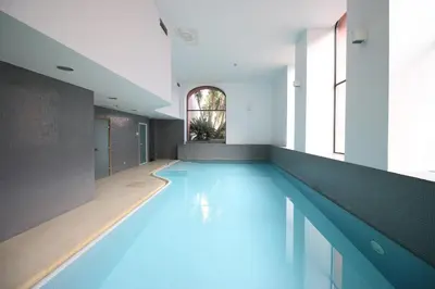 an indoor swimming pool with blue water in a building at Douro Senses Apartment in Porto