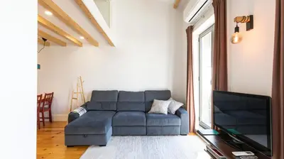a living room with a blue couch and a tv at Stylish Duplex with Balcony in Porto by LovelyStay in Porto
