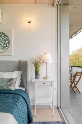 a bedroom with a bed and a table with a lamp at HostWise - Modern Flat w/ Balcony, Garage & Pool in Vila Nova de Gaia