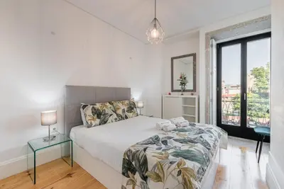 a white bedroom with a bed and a window at GuestReady - Rose Apartment in Porto