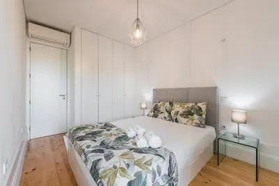 a bedroom with a large bed with white walls at GuestReady - Rose Apartment in Porto