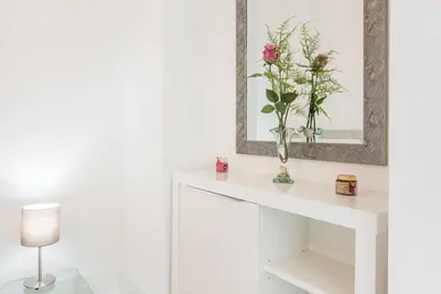 a white console table with a mirror and a vase with flowers at GuestReady - Rose Apartment in Porto