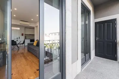 a balcony with a black door and a living room at GuestReady - Rose Apartment in Porto