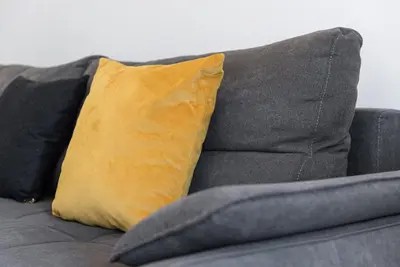 a yellow pillow sitting on top of a gray couch at GuestReady - Rose Apartment in Porto