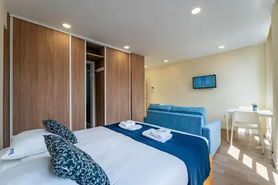 a bedroom with a large bed and a blue chair at Close to Everything Your Oporto Blue PRM 2F in Porto