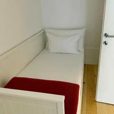 a small white bed with a red and white pillow at Apartment in Market Bolhão- W Views 2F in Porto
