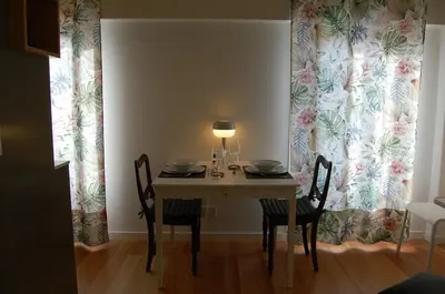 a dining room with a table and chairs and a curtain at Penthouse Inn Bolhão in Porto