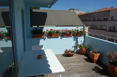 a balcony with potted plants and a white table at Penthouse Inn Bolhão in Porto