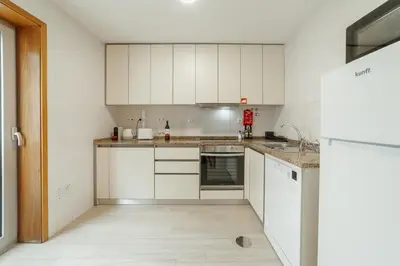 a kitchen with white cabinets and white appliances at Stylish Flat by Hosty in Porto