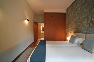 a bedroom with a bed and a stone wall at Spot Apartments Sao Bento in Porto