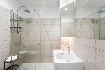 a white tiled bathroom with a sink and a shower at GuestReady - Unfolded in Porto