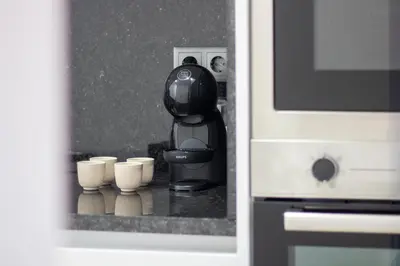 a coffee machine with cups on a counter next to a microwave at Quiet Duplex w Patio in Lapa by LovelyStay in Porto