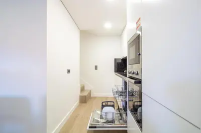 a kitchen with white walls and a glass partition with stools at Quiet Duplex w Patio in Lapa by LovelyStay in Porto