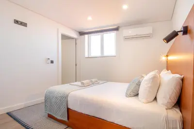 a bedroom with a bed with white sheets and a window at Quiet Duplex w Patio in Lapa by LovelyStay in Porto