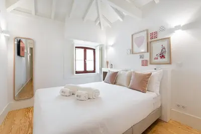 a white bedroom with a large white bed with towels on it at GuestReady - Clérigos Tiles House in Porto