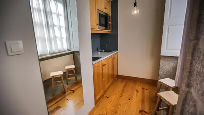 a kitchen with wooden cabinets and a table and chairs at My Ribeira Guest House in Porto