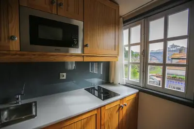 a kitchen with a sink and a microwave and windows at My Ribeira Guest House in Porto