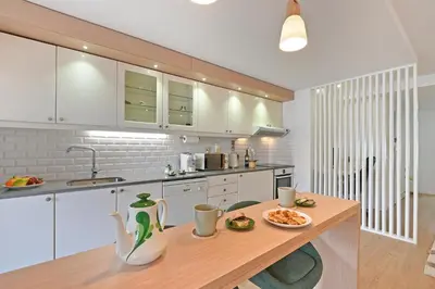 a kitchen with white cabinets and a wooden table at White Stripes House of Music in Porto