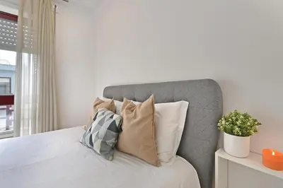 a white bedroom with a bed with pillows at White Stripes House of Music in Porto