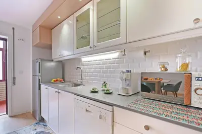 a kitchen with white cabinets and a sink at White Stripes House of Music in Porto