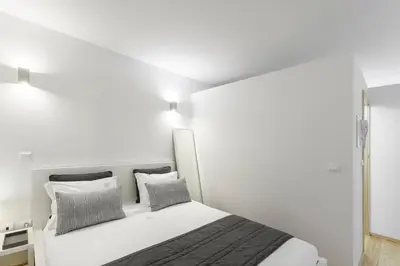 a white bedroom with a bed with two pillows at BO - Almada in Porto