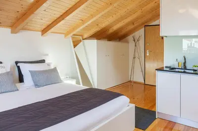 a bedroom with a white bed and a kitchen at BO - Almada in Porto